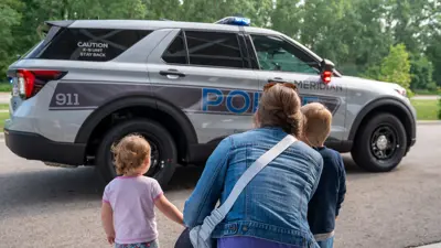 Mother a two kids looking at a Meridian Township Police cruiser