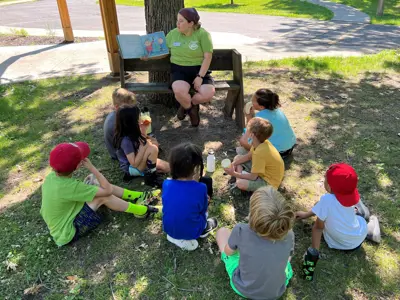 Harris Nature Center summer camp counselor reading a book to a group of children