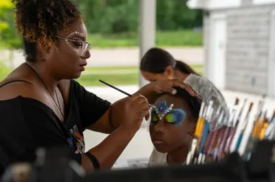 Woman painting the face of a young girl