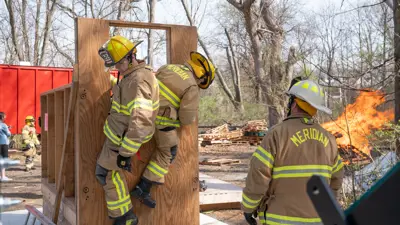 Two firefighters climbing out of a window during a training exercise