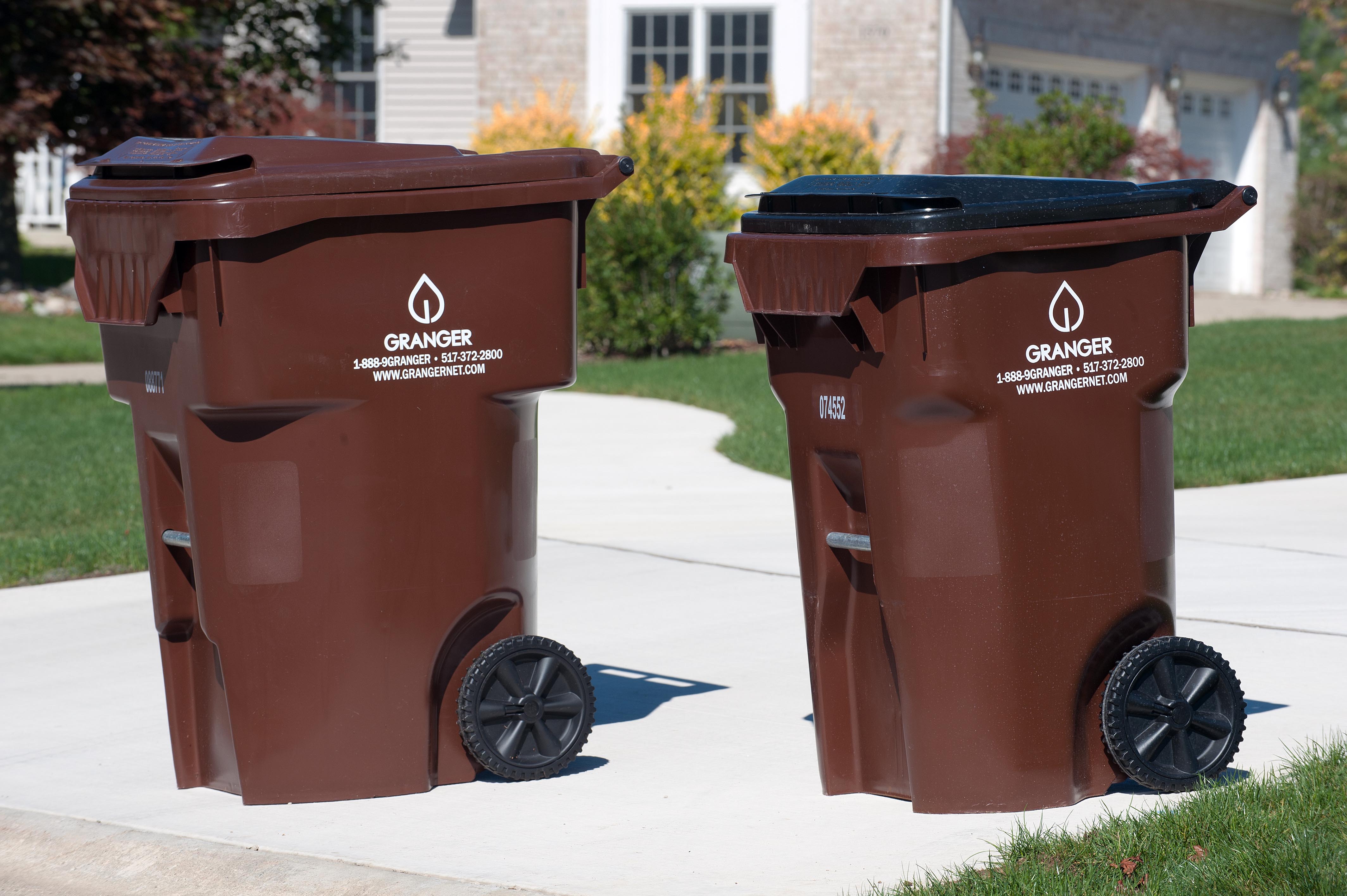 Two Granger Waste trashcans on a curb