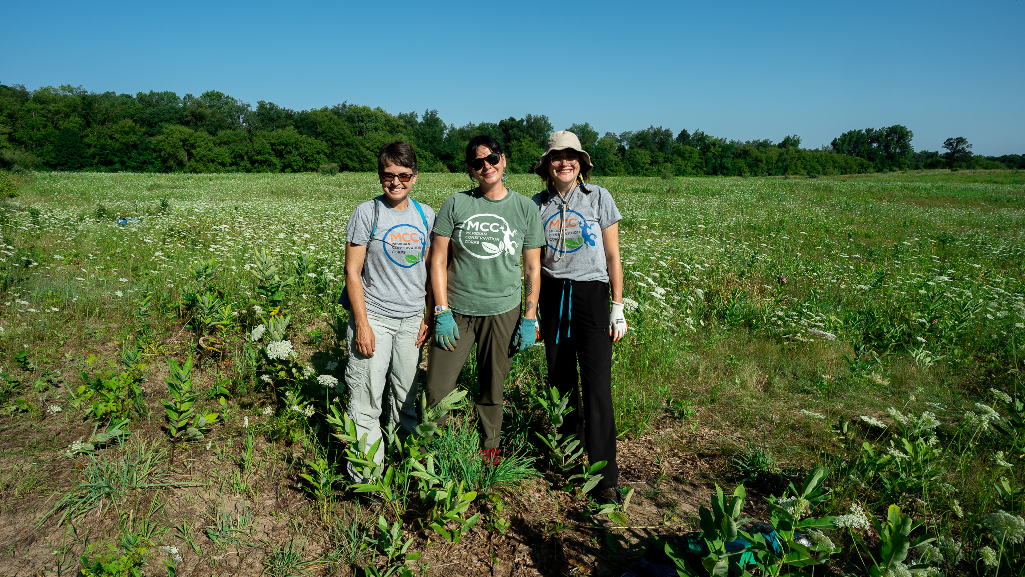 Land Stewardship Coordinator Emma Campbell posing with two MCC volunteers at a land preserve